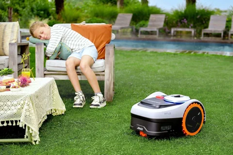 La tondeuse Segway Navimow i2 AWD posée sur une pelouse luxuriante alors qu'un enfant dort à proximité.