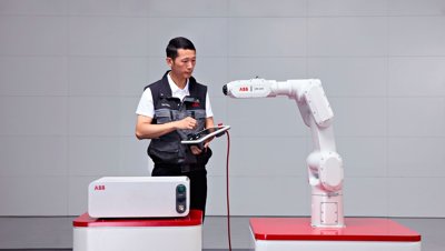 Inženýr programující robotické rameno ABB IRB 1200 pomocí tabletového ovladače.